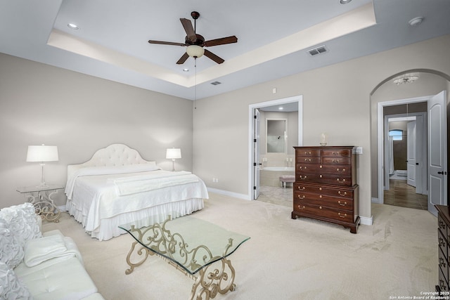 bedroom with arched walkways, a raised ceiling, visible vents, and light carpet
