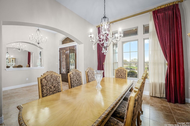 dining space featuring baseboards, a healthy amount of sunlight, arched walkways, and an inviting chandelier