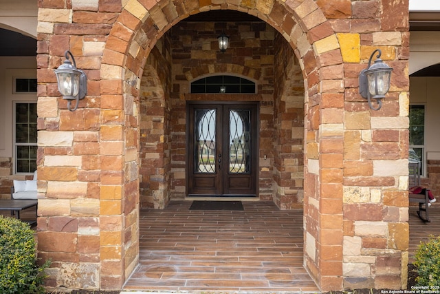 property entrance with stone siding, french doors, and brick siding