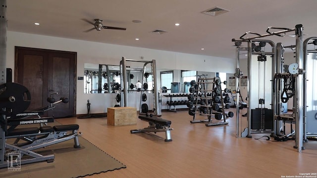 exercise room with a ceiling fan, visible vents, and wood finished floors