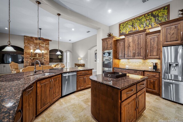 kitchen featuring arched walkways, stainless steel appliances, a sink, open floor plan, and decorative backsplash