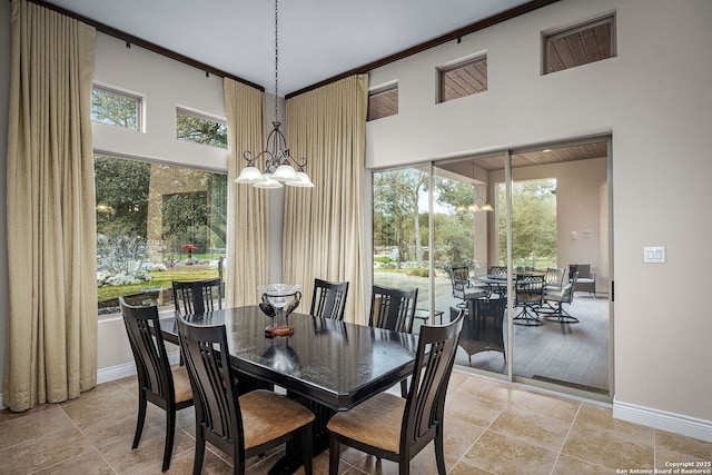 dining room with a chandelier, a towering ceiling, and baseboards