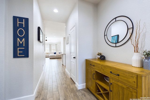 hall with light wood-style floors, baseboards, and recessed lighting