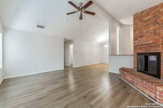 unfurnished living room with lofted ceiling, a fireplace, wood finished floors, and visible vents