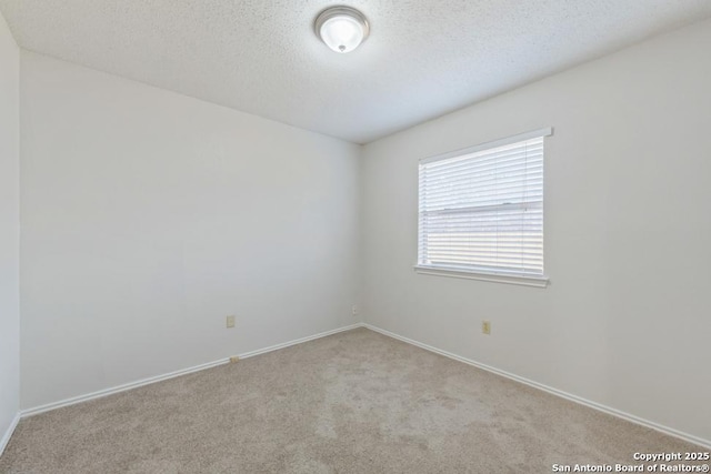 carpeted empty room featuring a textured ceiling and baseboards