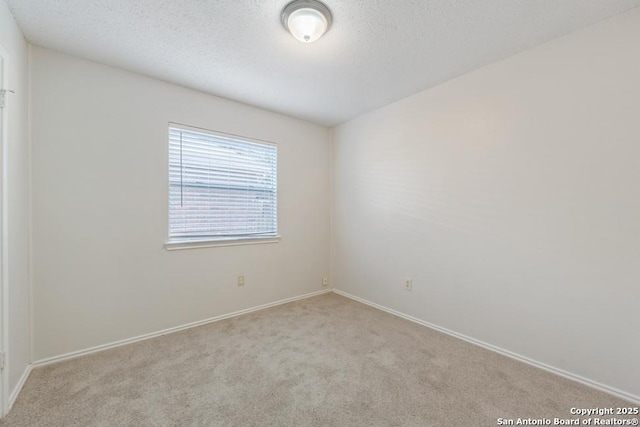 carpeted empty room with a textured ceiling and baseboards