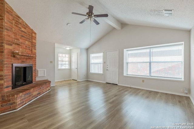 unfurnished living room with vaulted ceiling with beams, a textured ceiling, a fireplace, and wood finished floors