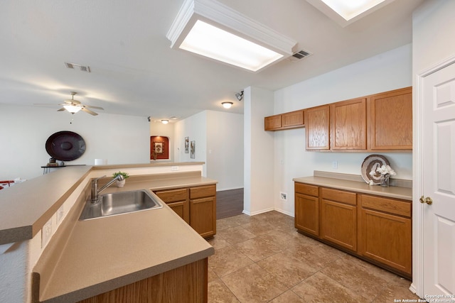 kitchen featuring visible vents, brown cabinets, a sink, and light countertops