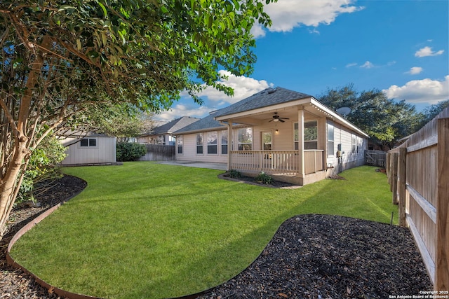 back of house with a ceiling fan, an outbuilding, a fenced backyard, and a yard