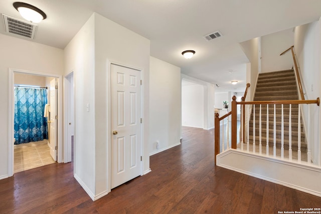 hall with visible vents, dark wood finished floors, and stairs