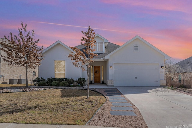 view of front of home featuring stucco siding, a lawn, an attached garage, central AC unit, and driveway