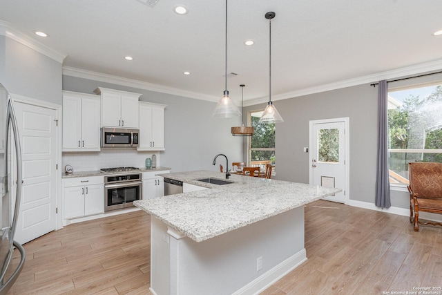 kitchen featuring light wood-style flooring, a sink, white cabinetry, appliances with stainless steel finishes, and decorative backsplash