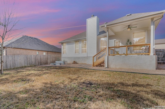 rear view of house with a ceiling fan, fence private yard, a yard, and a chimney