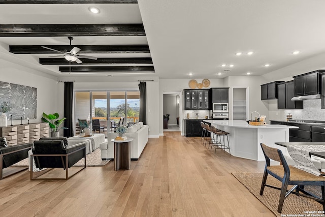 living room featuring baseboards, ceiling fan, beamed ceiling, light wood-type flooring, and recessed lighting