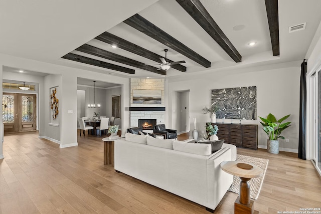 living room with light wood-style floors, beam ceiling, visible vents, and baseboards