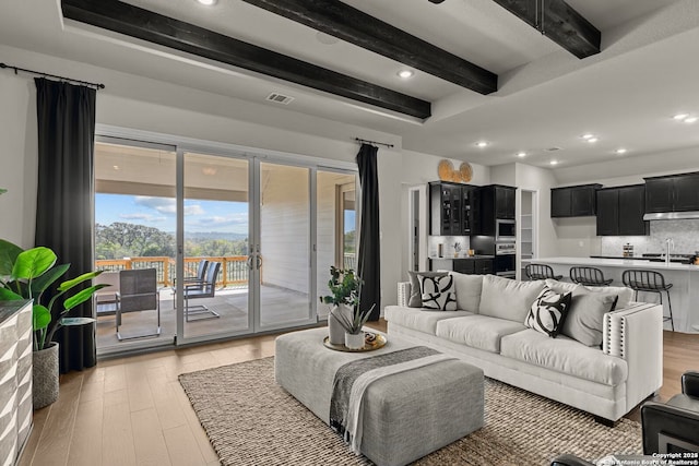 living room with light wood-style flooring, visible vents, beam ceiling, and recessed lighting