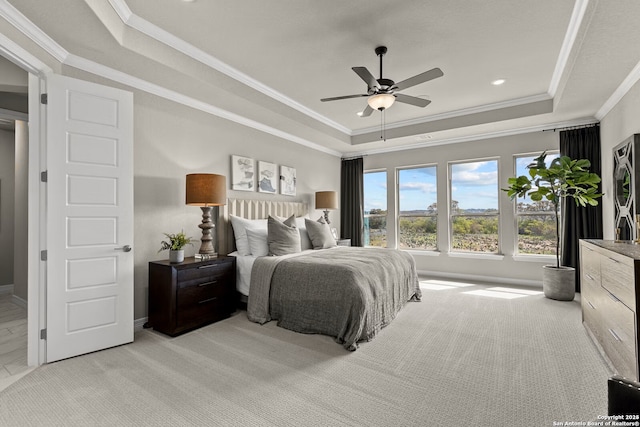 bedroom with baseboards, a raised ceiling, a ceiling fan, light colored carpet, and ornamental molding