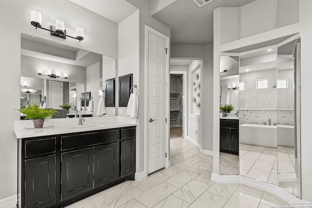 full bath with a walk in closet, marble finish floor, a garden tub, vanity, and baseboards