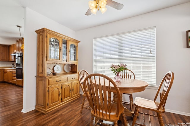 dining space with ceiling fan, baseboards, and dark wood finished floors