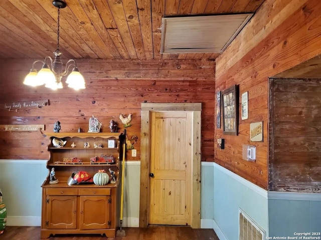 interior space featuring wooden walls, visible vents, wood ceiling, decorative light fixtures, and an inviting chandelier