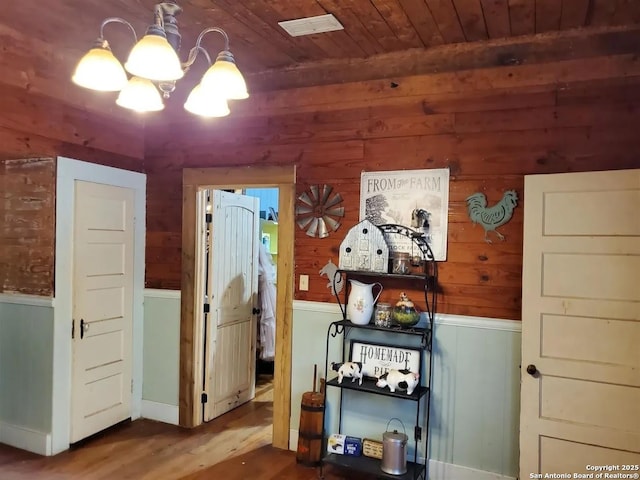 interior space with a chandelier, wooden ceiling, wainscoting, and wood finished floors