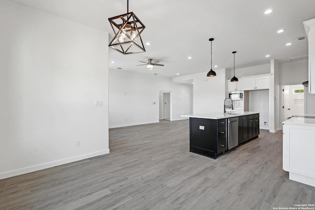 kitchen featuring recessed lighting, stainless steel appliances, open floor plan, light countertops, and light wood finished floors