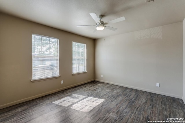 spare room featuring dark wood-style floors, ceiling fan, and baseboards