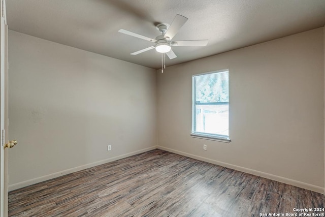 unfurnished room with wood finished floors, a ceiling fan, and baseboards