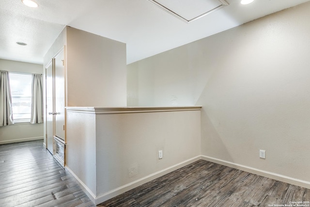 corridor featuring visible vents, baseboards, and wood finished floors