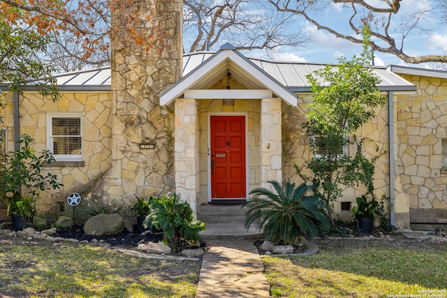 entrance to property with stone siding, a chimney, metal roof, crawl space, and a standing seam roof