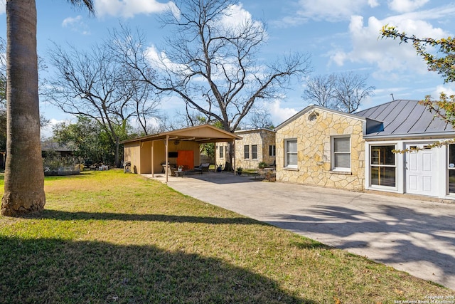 view of front of home with a front yard, a standing seam roof, metal roof, stone siding, and driveway