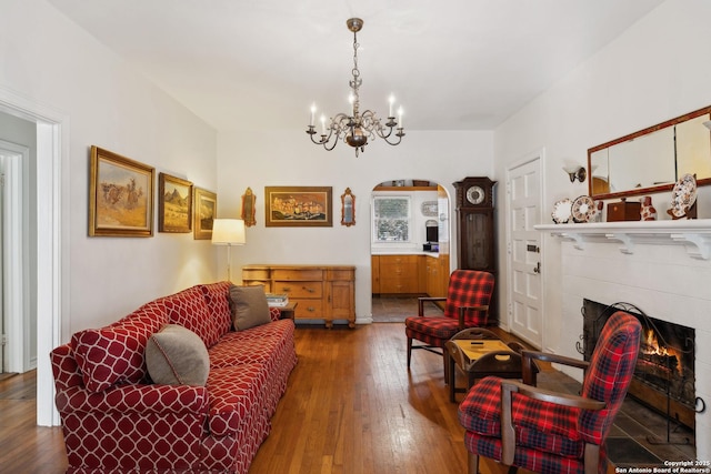 living room featuring an inviting chandelier, a lit fireplace, arched walkways, and hardwood / wood-style floors