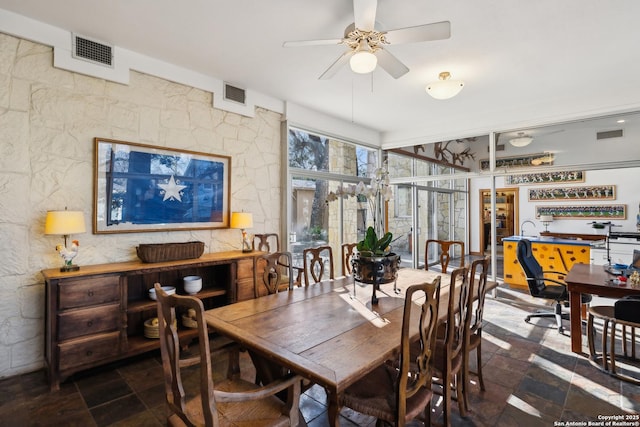 dining area with a ceiling fan, visible vents, and stone tile floors