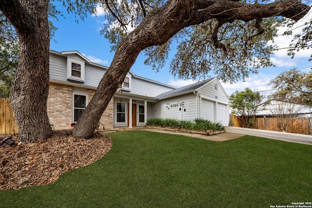 traditional-style house with an attached garage, a front yard, fence, and brick siding