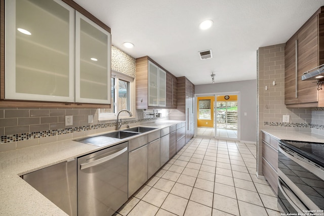 kitchen featuring light tile patterned floors, visible vents, decorative backsplash, glass insert cabinets, and stainless steel appliances