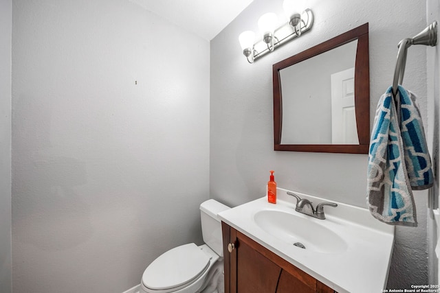 half bath featuring vanity and toilet