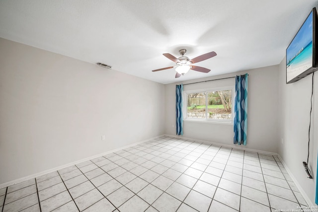 empty room with baseboards, light tile patterned floors, visible vents, and a ceiling fan