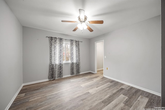 unfurnished room with a ceiling fan, baseboards, and wood finished floors