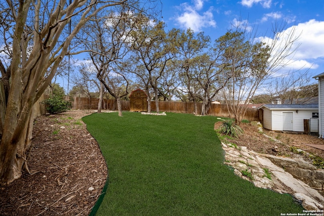 view of yard featuring an outbuilding, a storage unit, and a fenced backyard