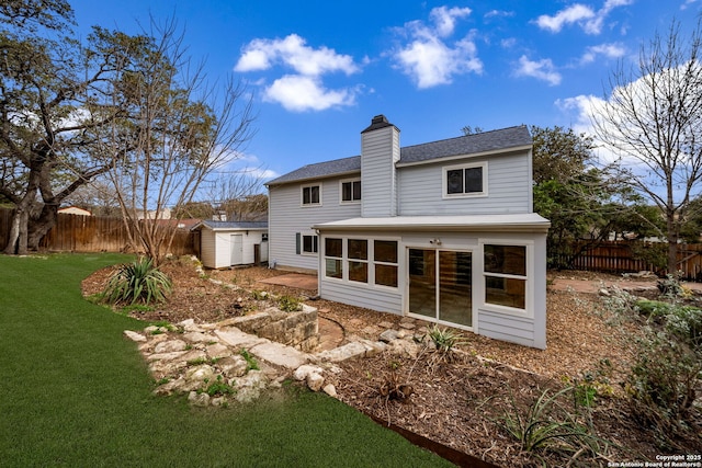 back of house with a yard, a chimney, a shed, a fenced backyard, and an outdoor structure