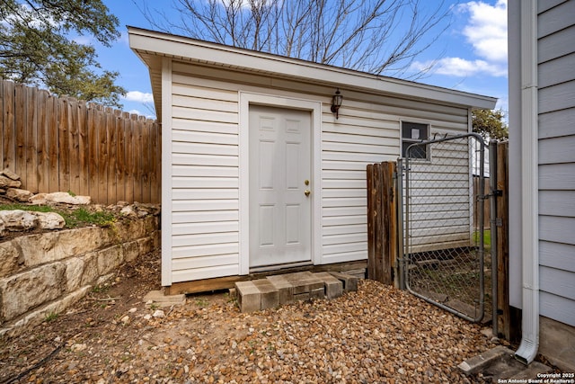 view of outbuilding featuring an outdoor structure, fence, and a gate