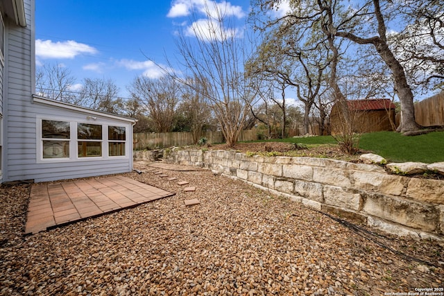 view of yard featuring a patio area, a fenced backyard, and an outdoor structure