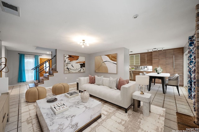 living area featuring light tile patterned floors, stairs, visible vents, and track lighting