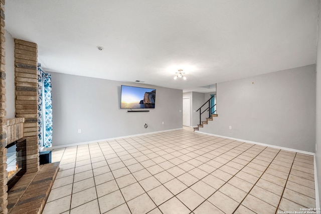 below grade area with stairs, light tile patterned floors, a brick fireplace, and baseboards