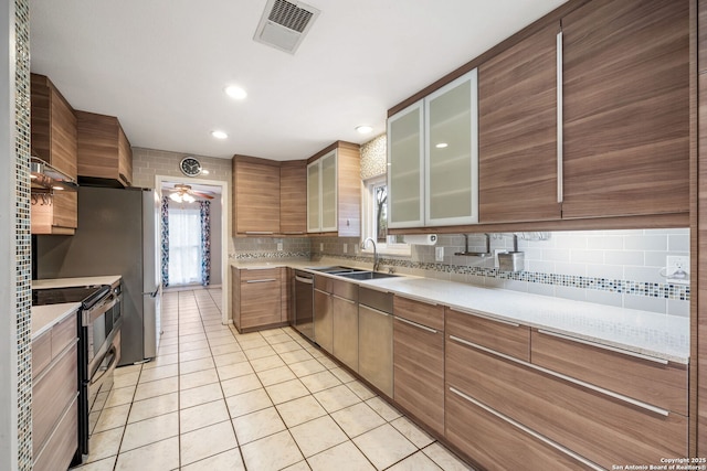 kitchen with light tile patterned floors, stainless steel appliances, a sink, visible vents, and tasteful backsplash