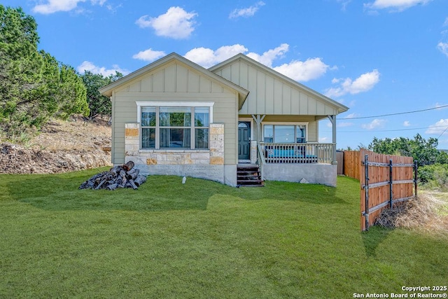 view of front facade featuring covered porch, fence, board and batten siding, and a front yard