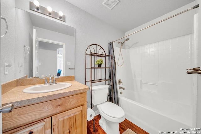 full bathroom featuring visible vents, a textured wall, toilet, vanity, and wood finished floors