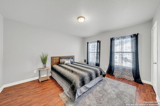 bedroom featuring a textured ceiling, wood finished floors, and baseboards