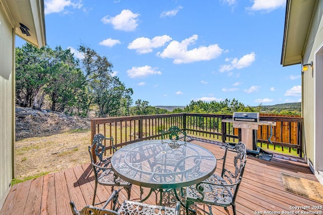 wooden deck with outdoor dining area and area for grilling