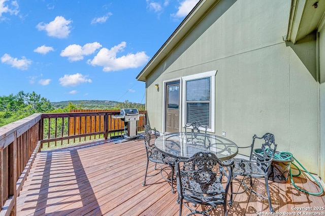 wooden terrace with outdoor dining area and grilling area